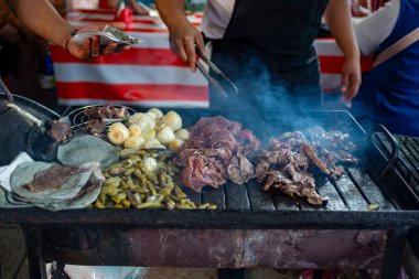 Bir satıcı, et ızgarasında soğan, nopales ve mısır tortillası pişirir. Izgara cecina.