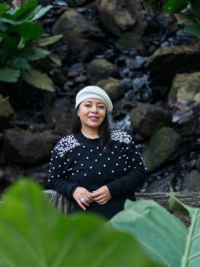 Hoş bir suratı olan bir kadının portresi. Tropik bir ormanın ortasında köprüye yaslanmış.