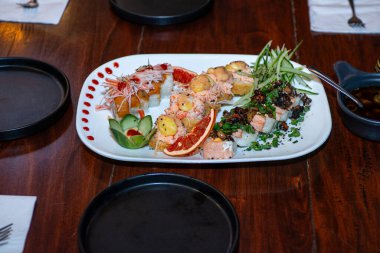 Lezzetli ve iştah açıcı suşi ruloları ve beyaz tabakta deniz ürünleri..