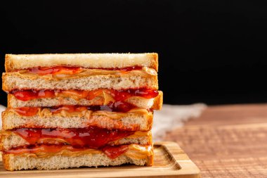 Tahtaya istiflenmiş fıstık ezmeli ve reçelli sandviç. Kapat..