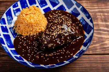 Ahşap bir masada servis edilen mavi ve beyaz desenli tabakta pirinçli tavuk köftesi tabağı..