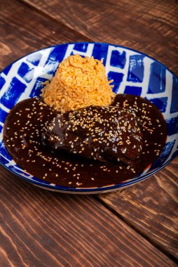 Ahşap bir masada servis edilen mavi ve beyaz desenli tabakta pilavlı tavuk köftesi..