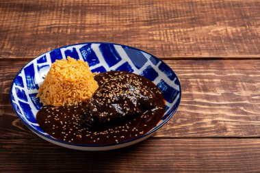 Ahşap bir masada servis edilen mavi ve beyaz desenli tabakta pilavlı tavuk köftesi..