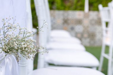 Beyaz sandalyeye bağlanmış çingene çiçeklerinin ayrıntıları, düğün töreni için hazırlanmış koridor..