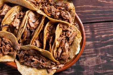 Geleneksel tacos al pastor ahşap bir masada kil tabakta servis edilir..