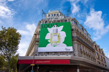Paris, Fransa - 24 Ekim 2025: Paris, Fransa 'nın ünlü bir mağazası olan Galeries Lafayette' in cephesini kaplayan Loewe parfümleri için büyük reklam panoları