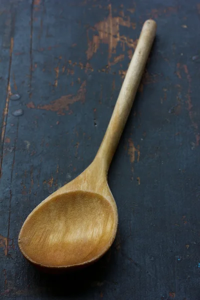 Cucchiaio da cucina in legno su un vecchio tavolo nero, primo piano, messa a fuoco selettiva. stile rustico. profondità di campo poco profonda — Foto Stock