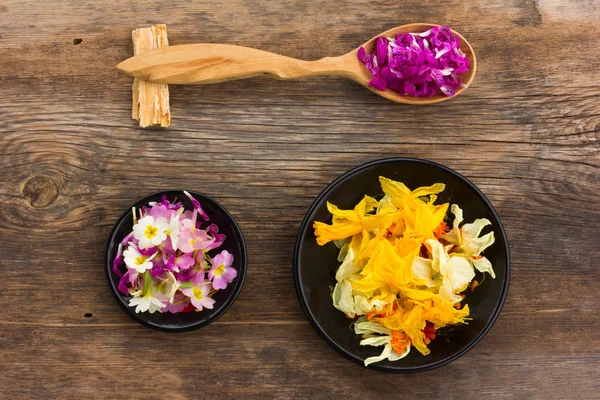 Verse en gedroogde bloemblaadjes in een houten lepel op het oude bord. Aromatherapie, kruidenthee, homeopathische geneeskunde. — Stockfoto