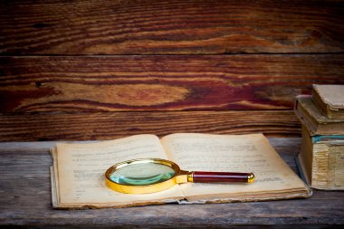 a magnifying cam ve ahşap bir masa üzerinde kitapların bir yığınına ile eski Defteri'ni.