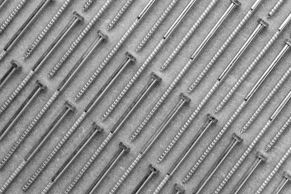 Set of new metal screws on a grey background are on the diagonal — Stock Photo, Image