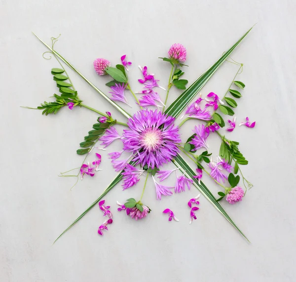 a bouquet of various purple flowers with green leaves on grey background