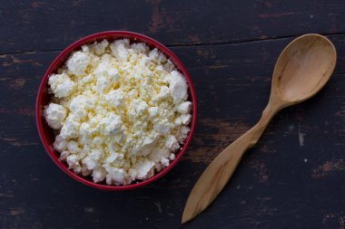 Kırmızı plaka beyaz sütlü lor ve ardıç tahta kaşıkla eski siyah ahşap masa. Üstten Görünüm yakın çekim