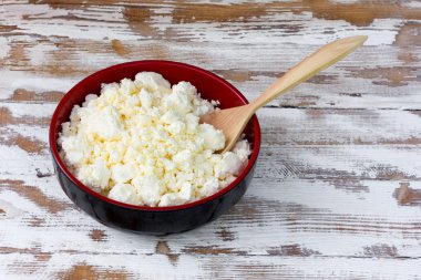 Eski Beyaz ahşap masa sarı taze peynir ve ardıç kaşık ile siyah plaka. Üstten Görünüm yakın çekim. seçici odak