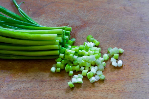 Gehakte groene uien op een oude houten hakken bestuur closeup — Stockfoto