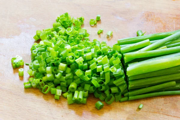 Gehakte groene uien op een oude houten hakken bestuur closeup — Stockfoto