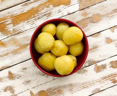 beyaz boya portre, üstten görünüm kalıntıları ile eski ahşap masa üzerinde kırmızı bir kase saflaştırılmış haşlanmış sarı patates