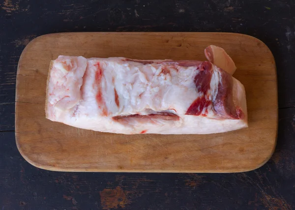 Egy nagy darab nyers sertéshús zsír egy vágódeszkát, egy régi rusztikus fekete konyhaasztalon, Vértes felülnézet — Stock Fotó