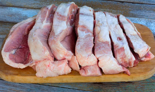 Duży kawałek mięsa surowe wieprzowe posiekane na kawałki na pokładzie cięcia, szczegół widok z góry — Zdjęcie stockowe