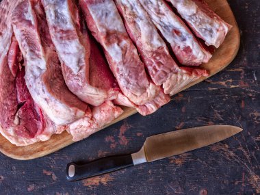 çiğ domuz eti büyük bir parçası bir eski rustik tabloyu siyah ve paslanmaz çelik mutfak bıçak, yukarıdan görmek bir kesme tahtası üzerinde parçalar halinde doğranmış. tonda fotoğraf