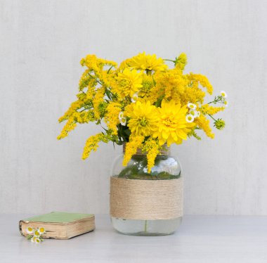 küçük eski kitap, bir buket çiçek krizantem, Altın Başak ve gri arka plan üzerinde bir cam vazo ev yapımı closeup papatyalar