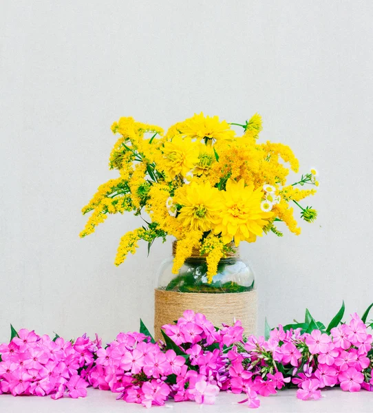 Un bouquet de fleurs chrysanthèmes, verge d'or et marguerites dans un vase parmi le Phlox sur un fond gris. photo teintée — Photo