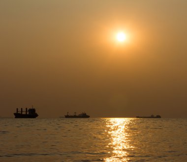 Gün batımına karşı denizde gemilerin siluetleri. sığ derinlik-in tarla