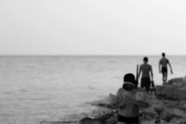 The blurred image of the sea shore with vacationers in the evening. black and white photo — Stock Photo, Image