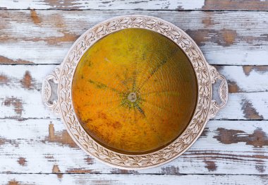 Eski Beyaz ahşap masa, üstten görünüm yakın çekim altın tepside olgunlaşmış kavun