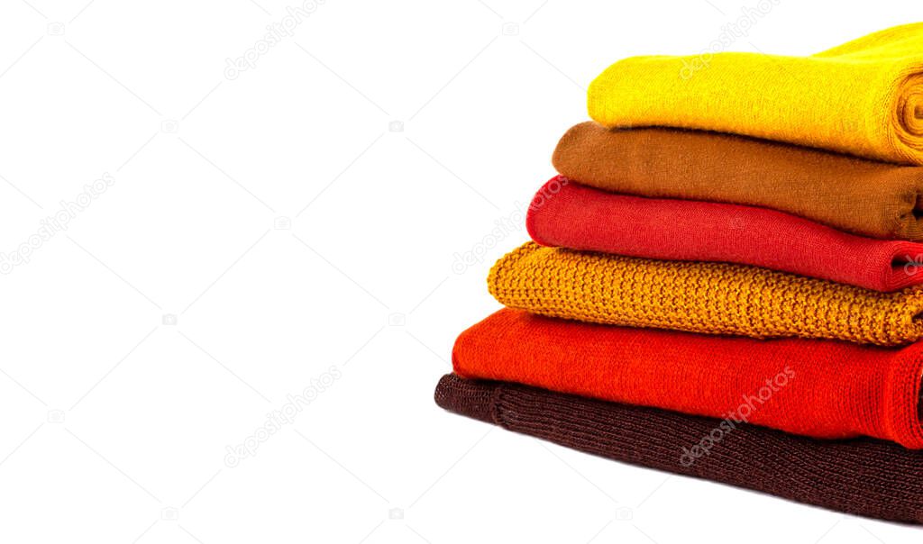 Stack of colorful folded sweaters isolated on white background with copy space