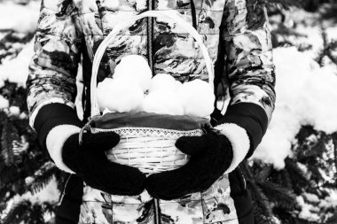 Siyah örgü eldivenlerinde bir sepet kartopu tutan bir kız. Siyah beyaz bir fotoğraf.