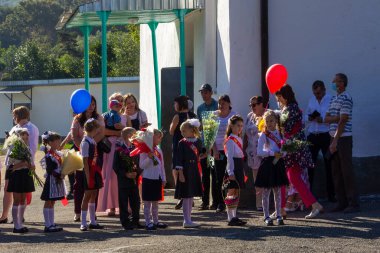 Adygea, Rusya - 1 Eylül 2020: Birinci sınıflar çiçek buketleri ve aileleri bilgelik gününde resmi törenin başlamasını bekliyorlar.