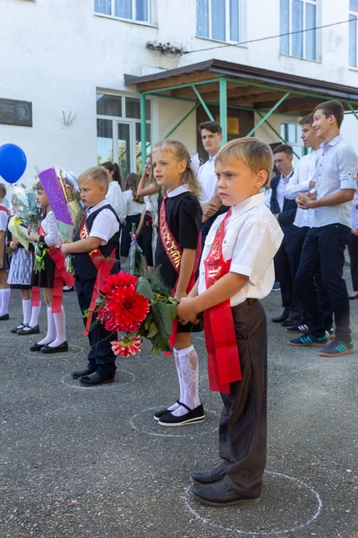 ロシア アディゲ 2020年9月1日 知識の日に厳かなラインで花と高校生の花束で1年生に入った子供たち — ストック写真