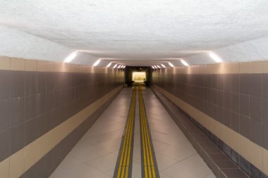 lighted underground passage under the highway, with a low ceiling clipart
