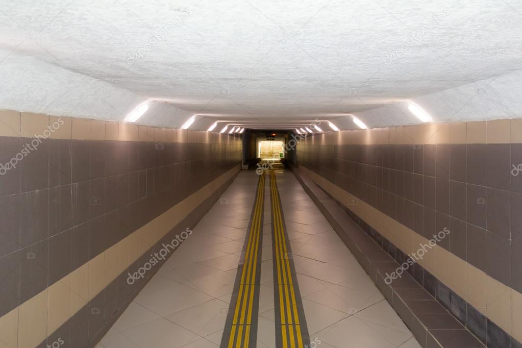 lighted underground passage under the highway, with a low ceiling
