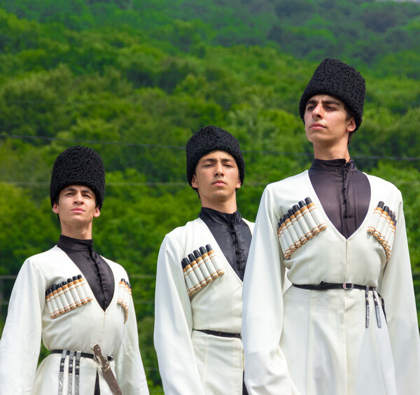 Young guys in Adyghe national costumes dancing traditional dance at an ethnofestival in the Foothills of Caucasus in Adygea