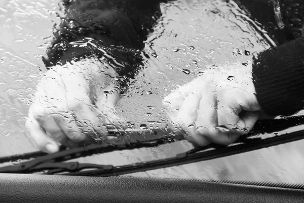 O homem na chuva repara um limpador de janela de carro em preto e branco — Fotografia de Stock