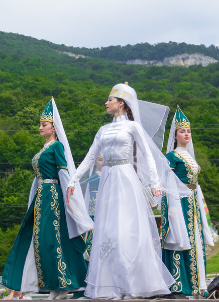 Female dancers in traditional costumes Circassian green hills in the background. Ethnic festival in the foothills of the Western Caucasus in Adygea