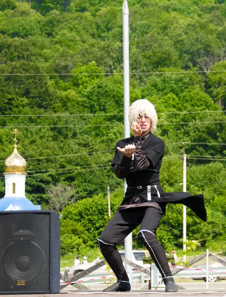 Hombre adyg bailando danza tradicional en el escenario, sobre un fondo de bosque verde. Fiesta étnica en las estribaciones del Cáucaso Occidental en Adygea — Foto de Stock