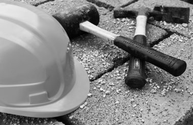 koruyucu kask ve gri beton üzerinde eski çekiç blok closeupt, siyah beyaz fotoğraf