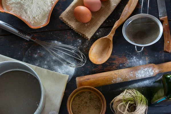 Eine Reihe alter Küchenutensilien aus der Nahsicht von oben. Küchentisch im rustikalen Stil. Produkte zum Backen von Mehl, Eiern, Salz. — Stockfoto