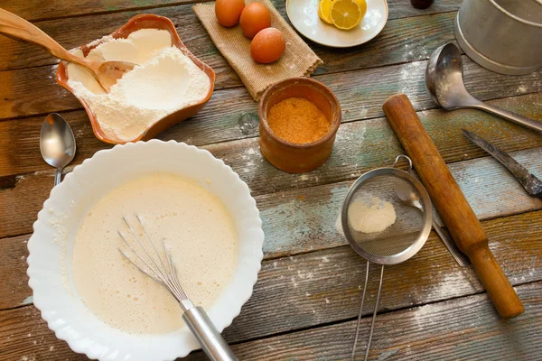 Zubereitung des Teiges in einer rustikalen Küche. Weizenmehl, Teig, Eier, eine Zitrone und Küchenutensilien auf Holztisch. — Stockfoto