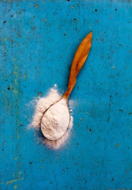 Tahta kaşık un eski parlak mavi bir arka plan üzerinde dolu ardıç üzerinden