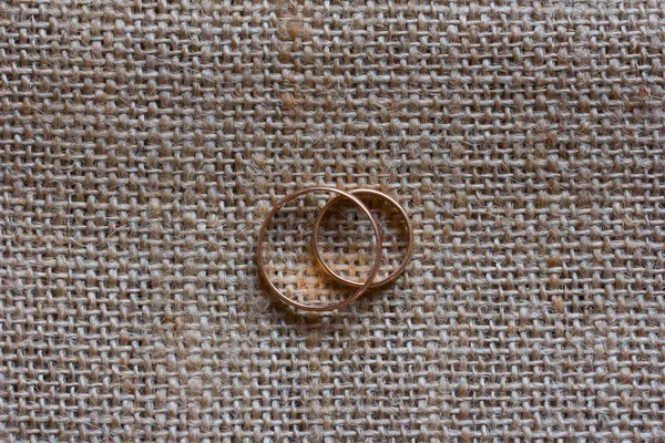 Male and female wedding rings made of gold on a background of burlap. The concept of legal relationship — Stock Photo, Image