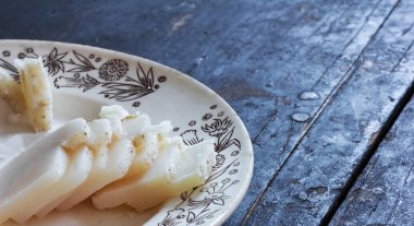 Domuz yağı bir seramik tabak eski siyah ahşap masa üzerinde küçük parçalar halinde kesip tuzlu. Rustik tarzı. Kırsal mutfak konsepti. Seçici odak, yakın çekim. Metin için özgür yer. Kopya alanı