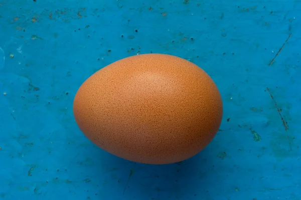 Brown chicken egg in shell on an old blue background. Top view closeup. Shallow depth of field — Stock Photo, Image