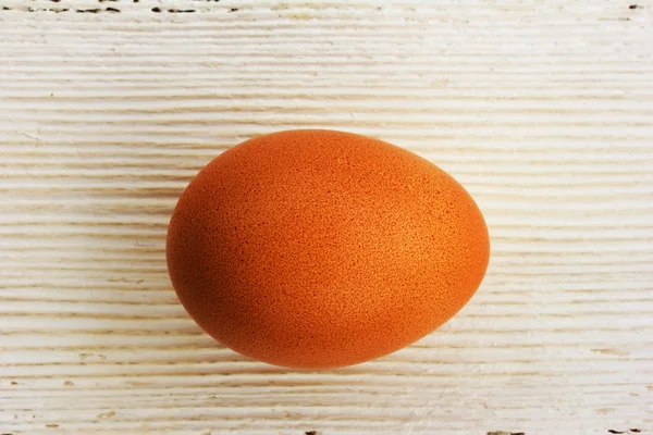 Brown chicken egg in shell on a white wooden background. Shallow depth of field. Top view closeup. — Stock Photo, Image