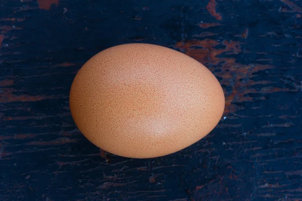 Brown chicken egg in shell on a white wooden background. Shallow depth of field. Top view closeup. — Stock Photo, Image