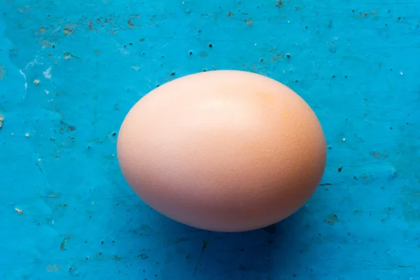 Pink chicken egg in the shell on an old blue background. Top view closeup. Shallow depth of field — Stock Photo, Image