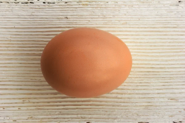 Brown chicken egg in shell on a white wooden background. Shallow depth of field. Top view closeup — Stock Photo, Image