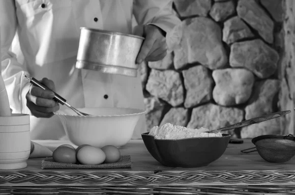 Weizenmehl und Eier inmitten von Männern, die Mehl für den Teig sieben. Konzept der rustikalen Küche, selektiver Fokus. Kopierraum. Freiraum für Text. Schwarz-Weiß-Foto — Stockfoto